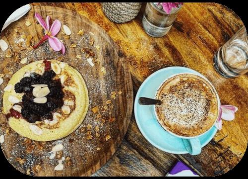Pancake with berries, granola and a cappuccino on a wooden board